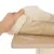 Mano levantando un cojín beige de tela suave sobre una base de madera clara, mostrando una tira de velcro visible en la superficie.
