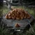 Dry food in triangular shape on stone, size 7-9 mm. Background shows nature with cat in grass.
