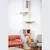 Tall scratching post with multiple levels, hammock, cave and lounging areas made of grey fabric. An orange cat is climbing down from the lower lounging area.