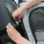 Hand attaches a grey transport bag with mesh window to the car seat using a strap system.
