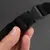 Close-up of a black plastic click fastener on a nylon strap, held by a hand.