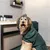 Dog with green bathrobe from kooa in a bathroom, with kooa care products and towels in the background.