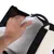 Hand opening zip of a bag with soft white lining and black outer material. A flexible cable is visible inside.