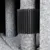 Brosse noire en plastique fixée autour d’un poteau recouvert de tissu gris, partie d’un arbre à chat ou griffoir visible sur l’image.