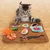 Котёнок играет с игровой подстилкой с игрушками-суши и цветными тканевыми элементами.