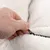 Close-up of a hand opening or closing a black zip on white, fluffy fabric.