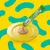 Creamy treat being squeezed from a green Dreamies Creamy sachet onto a yellow plate, showing product texture and serving suggestion.