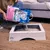 Sanicat Kitten Litter is poured into a white wooden cat toilet. Packaging shows a kitten and the text 'Oxygen Power'.