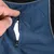 Close-up of blue fabric material with a black zip being opened.