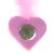 Jouet en forme de cœur rose en feutre avec une boule verte au centre et plume rose sur le dessus, matériaux visibles : feutre, herbe compressée, plume.