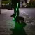 Chien avec collier et laisse lumineux verts, tenu par une personne sur un trottoir la nuit. Collier et laisse éclairés pour visibilité nocturne.