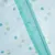 Close-up of a turquoise zip on white fabric with colourful dots.