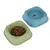 Two plastic feeding bowls, green with dry food and blue for water. Square shape with rounded corners.