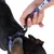 Main tenant une laisse bleue à motifs, mousqueton accroché à un collier bleu avec boucle en plastique sur le cou d’un chien noir. Étiquette visible sur la laisse.