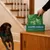 Earth Rated lavender poo bags, 300 pieces, Grab & Go single roll. Hand takes bag from dispenser box, dog in background.