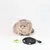 Chat beige assis avec une petite peluche grise sur la tête, devant trois jouets en tissu : un vert, un rond noir avec texte et un blanc avec ficelle noire.
