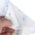 Close-up van een witte inleg met blauwe hondmotieven en pootafdrukken, vastgehouden door een hand.