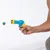 Hand hält eine blaue und gelbe Spielzeugpistole, die einen grünen Ball abschießt.