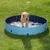 Piscina redonda azul para perros colocada sobre césped, con un perro de tamaño grande dentro y juguetes visibles en el agua.