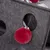Grey felt material with round openings and a red plush ball on a string, suitable as a toy or accessory.