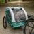 Grüner Fahrradanhänger Nomad Tales mit Netzabdeckung, Hund sitzt darin. Geeignet für den Transport von Haustieren.