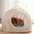 Cat basket made of light woven material with metal grid opening and blue polka dot cushion. Cat is lying relaxed inside.