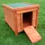 Wooden dog kennel with green roof, folding ramp and metal locks, placed on a lawn.