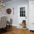 Cane che utilizza una porticina installata in una porta bianca. Interno con pavimento in legno e mobili da sala da pranzo visibili.