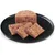 Close-up of meat pieces on a black plate, showing the texture and shape of the wet food.