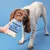 Dog holding a pack of Pooch & Mutt Fish, Potato & Pea complete wet food in its mouth, with a hand offering the product against a blue background.