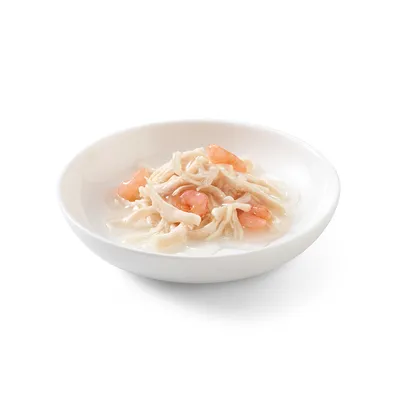 Ciotola bianca con strisce di pollo e gamberetti in salsa, pronta da servire.