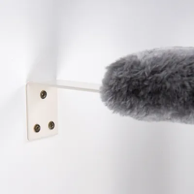 Grauer Fellaufsatz reinigt eine weisse Wandhalterung mit vier Schrauben. Demonstration der Reinigungsfunktion des Produkts.