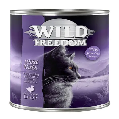 Conservă Wild Freedom Wild Hills, text vizibil: 100% grain-free recipe, Inspired by your cat's natural instincts, Chicken with Duck. Imagine cu pisică pe ambalaj.
