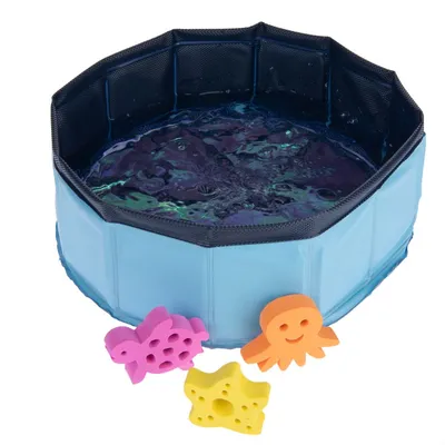 Piscina pieghevole blu per pet con acqua, tre giochi a forma di pesce viola, stella marina gialla e polpo arancione in spugna visibili davanti alla piscina.