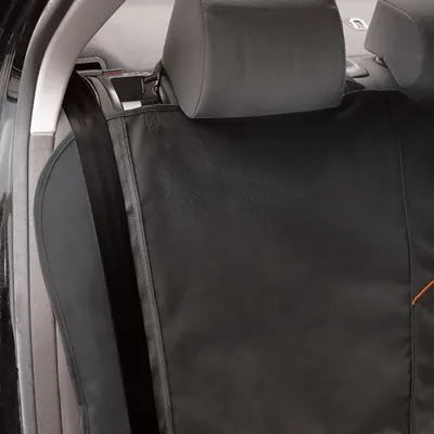 Musta auton istuinsuoja oranssilla korostuksella, kiinnitetty niskatukiin ja takapenkin selkänojaan.