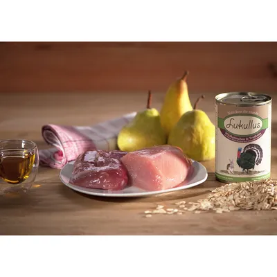 Burk med texten 'Lukullus Naturkost für Hunde, Wildkaninchen & Truthahn', rått kött på tallrik, tre päron, havregryn och ett glas vätska synliga.