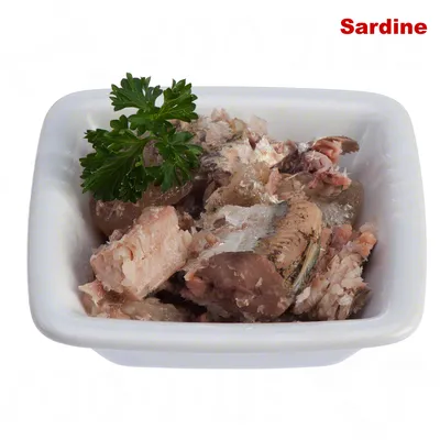 Kocky sardiniek v bielej miske, ozdobené vetvičkou petržlenu. Viditeľný nápis: Sardine.