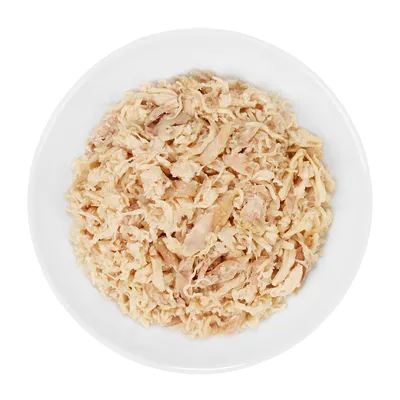 Schale mit zerkleinertem, hellbraunem Fleisch auf weißem Teller, Nahaufnahme des Futters.