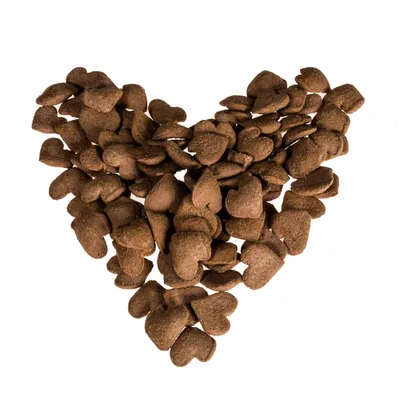 Piezas de pienso seco marrón en forma de corazón, dispuestas en forma de corazón. Textura y forma visibles de las piezas.