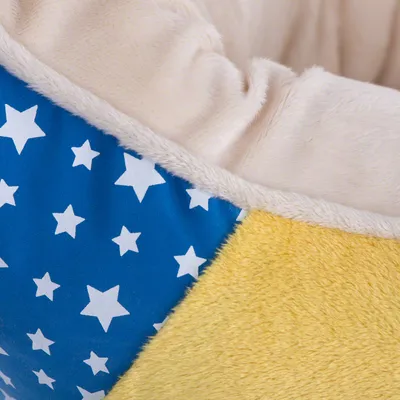 Detailansicht eines Haustierbetts mit blauem Stoff und weissen Sternen sowie gelbem und beigem Plüschmaterial.