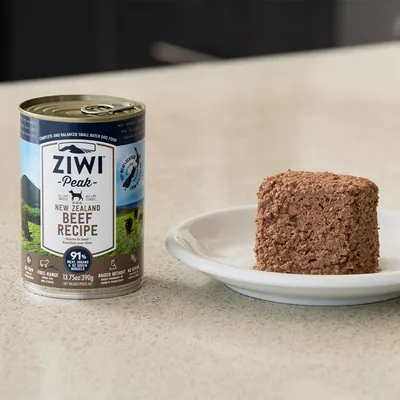 Boîte de pâtée pour chien Ziwi Peak New Zealand Beef Recipe 390 g, texte visible : 91 % viande, sans céréales, free-range. Portion de pâtée servie dans une assiette blanche à côté.