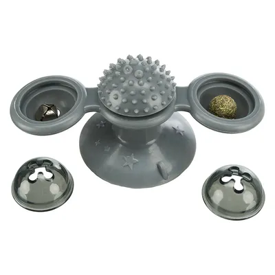 Šedá plastová hračka s přísavkou, dvěma miskami (jedna s rolničkou, druhá s kuličkou), střední část s bodlinkami, dvě průhledná víčka položená vedle.