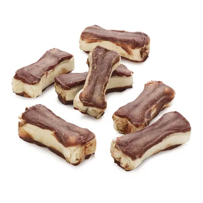 Sedem žuvacích pochúťok v tvare kosti, hnedo-bielej farby, bez viditeľného obalu alebo značky, na bielom pozadí.