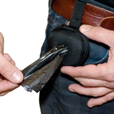 Black pouch dispenser with zip, attached to a belt. A hand pulls out a black dog waste bag.