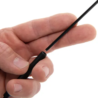 Hand som håller ett smalt svart plaströr med en borste i ena änden, synlig detalj av borsthuvudet och rörets öppning.