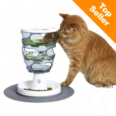 Pisică portocalie lângă un turn transparent cu tăvi verzi, folosit pentru hrănirea cu crochete. Colțul dreapta sus: text portocaliu „Top Seller”.