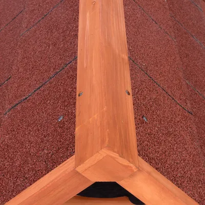 Detailweergave van roodbruin dakmateriaal met houten bekleding en schroefbevestiging.