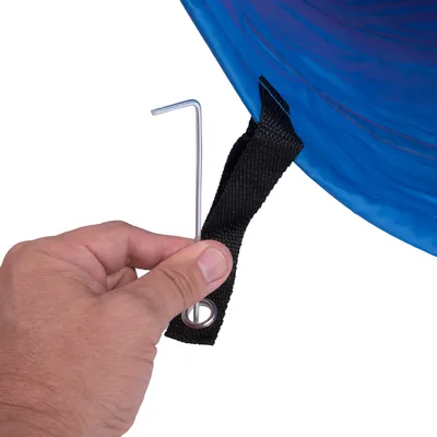 Hand zeigt, wie ein Metallhaken durch eine schwarze Schlaufe am blauen Material geführt wird. Demonstration der Befestigungsmethode.