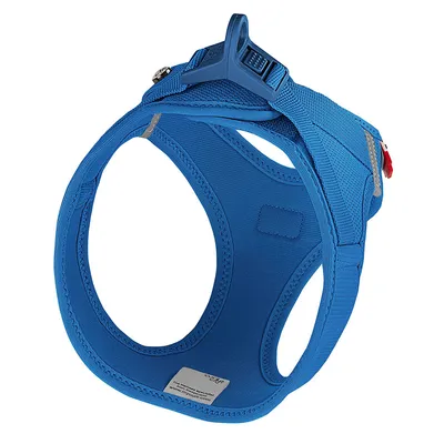 Blue dog harness with adjustable straps, sturdy buckle, and reflective details. Label with manufacturer information visible.