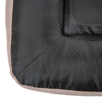 Vue rapprochée du dessous d’un coussin pour animal en tissu noir antidérapant à picots, avec fermeture éclair visible sur le côté.